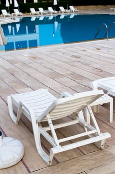 Back view of sunbed by blue swimming pool.