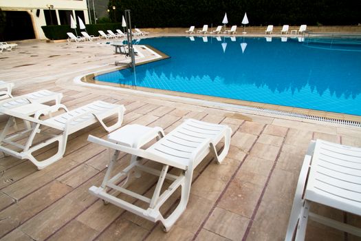 Sunbeds by blue swimming pool.
