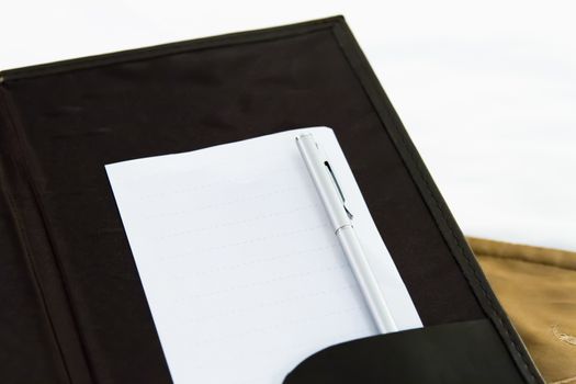 White blank note with pen on bed in hotel room.