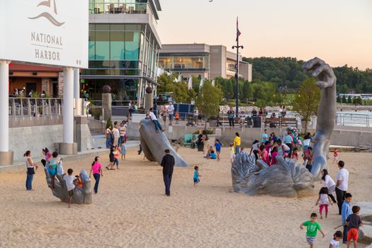 Children play on top of the awakening sculpture, a five piece aluminium figure of a giant man buried in the sand on Aug 28, 2014 at the National Harbor in Maryland, USA.