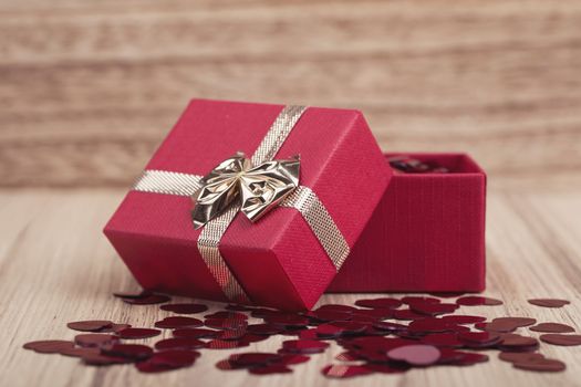 small red hearts confetti and present box on wooden background