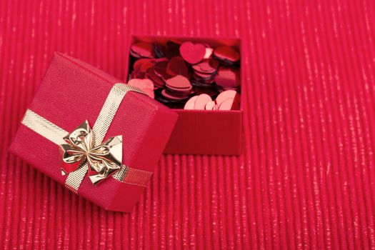 small red hearts confetti and present box on fabric background