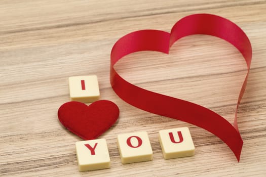 valentine's paper hearts on a wooden background , valentine's day , day valentine postcard with scrabble text I love you