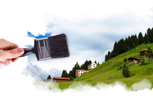 Male hand holding paint brush and painting Ayder Plateau in Rize, Turkey.