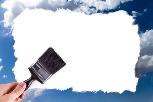 Male hand holding paint brush and painting blue and cloudy sky with copy space for your design, isolated on white background.