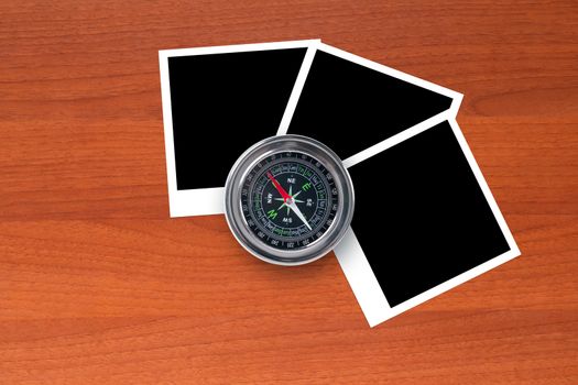 Blank, black picture frames with compass on wooden table.