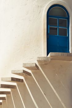 stairs leading to a door in cement wall with light and shadow