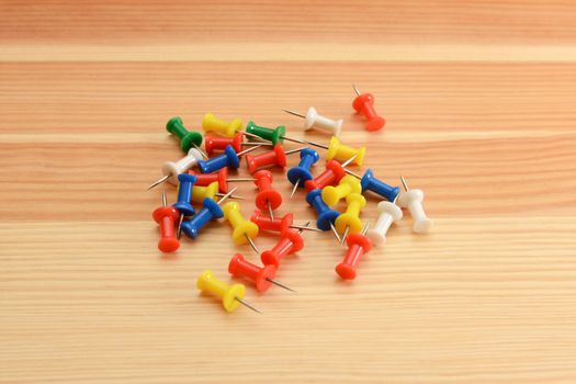 Coloured push pins - green, white, red, yellow and blue - on a wooden background