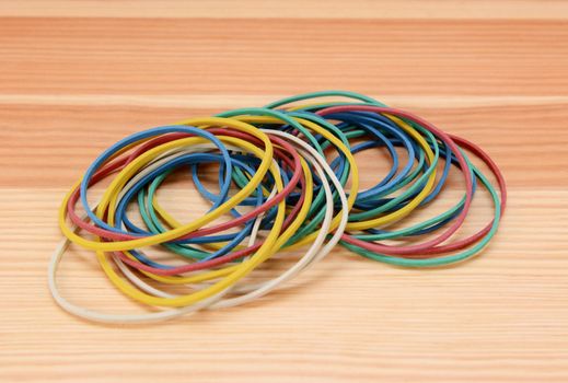 Large pile of coloured elastic bands on a wooden background