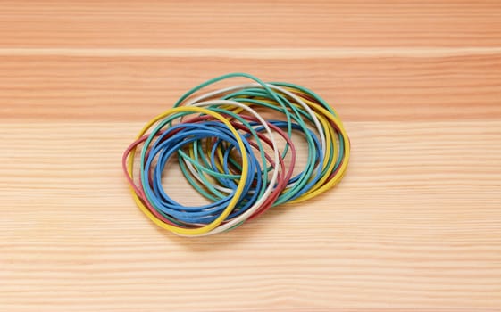 Small neat pile of coloured rubber bands on a wooden background