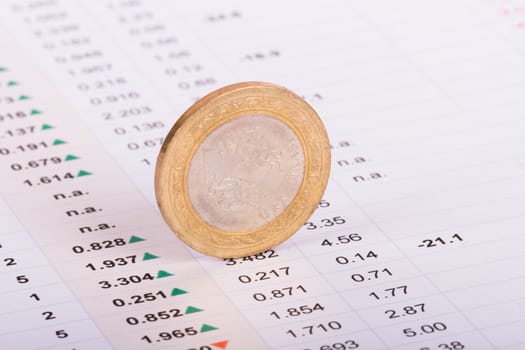 Coin standing on financial data results.