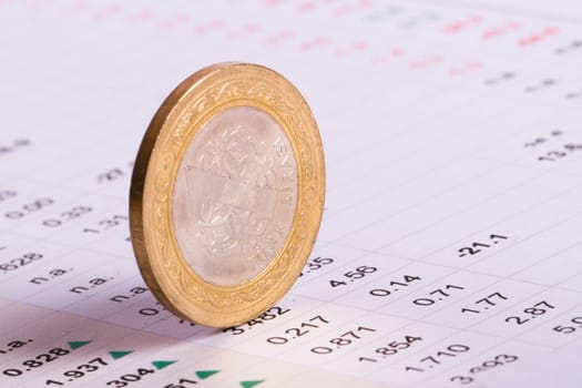 Close up view of coin standing on financial data results.