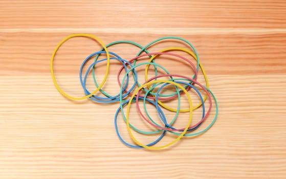Handful of coloured elastic bands scattered on a wooden background