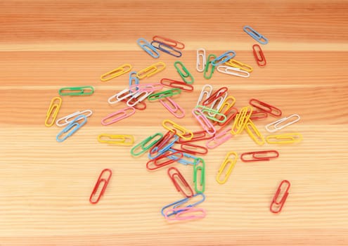 Multi-coloured paper clips scattered across a wooden background