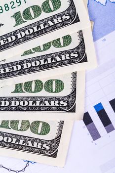 One hundred dollar banknotes on chart graphs.
