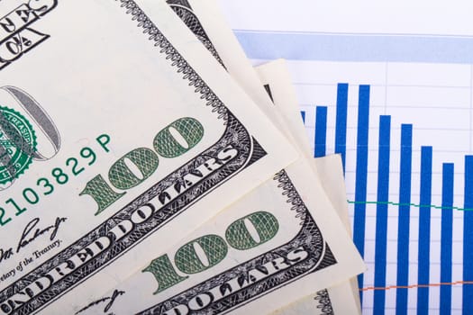 One hundred dollar banknotes on chart graphs.
