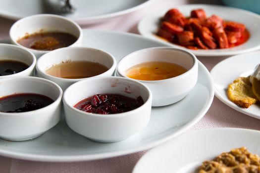 Breakfast service, jam and honey in white bowls on table.