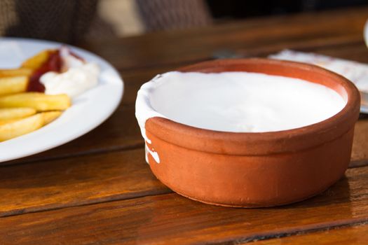 Yogurt in soil bowl on table.