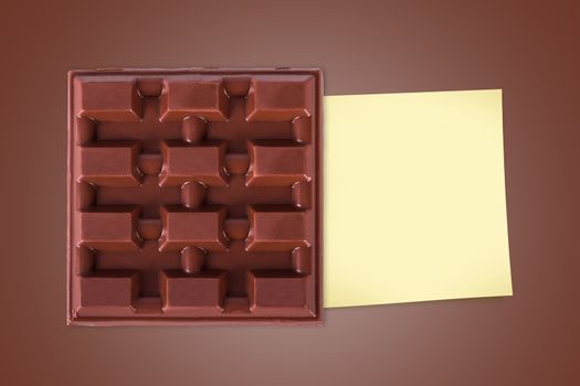 Top view of full milk bar chocolate with sticky note paper for your message on brown background.