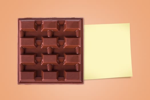 Top view of full milk bar chocolate with sticky post for your message on brown background.