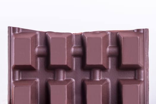 Close up view of broken milk chocolate bar piece, isolated on white background.