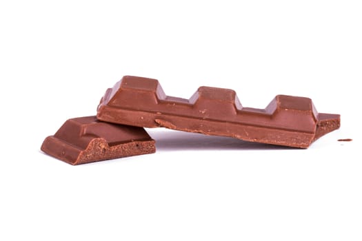 Broken milk chocolate bar pieces, isolated on white background.
