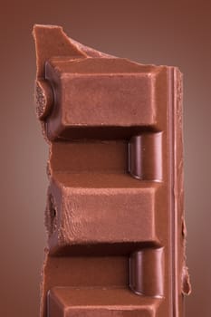 Sweet bar piece on chocolate color background.