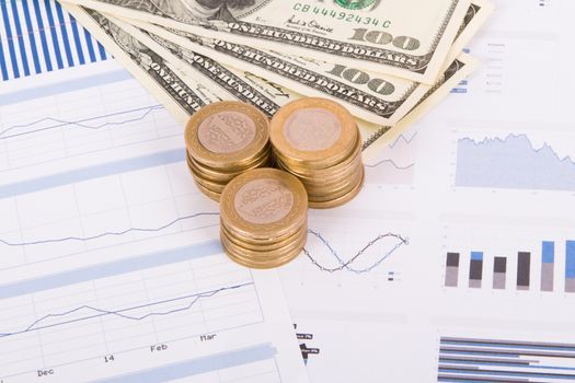 Dollar banknotes and coins on bar chart graphic results.