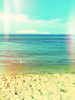 Sea and sand beach. Retro styled image with light leaks.