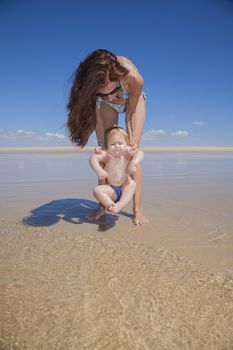 one year baby swimsuit does not like water in woman mother hands at beach next to Conil Cadiz Spain