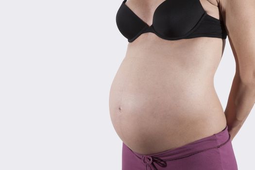 tummy of naked pregnant woman over white background