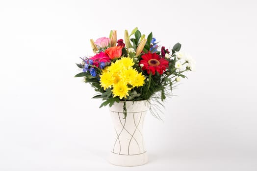 A beautiful flower arrangement in a vase set on a white islolated background.
