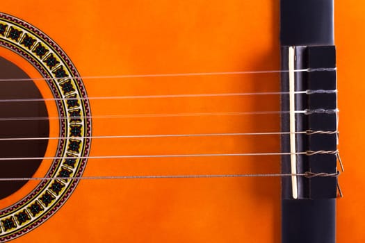 Detail view of orange wooden classical acoustic guitar.