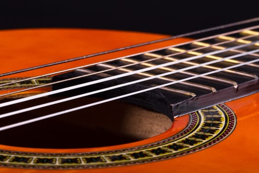 Close up view of classical guitar includes with strings, fingerboard and part of body.