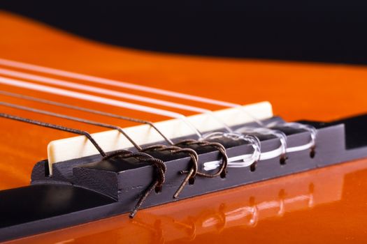 Macro view of orange wooden classical acoustic guitar.