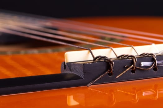 Detail view of orange wooden classical acoustic guitar.