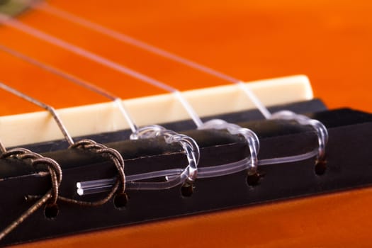 Detail view of orange wooden classical acoustic guitar.