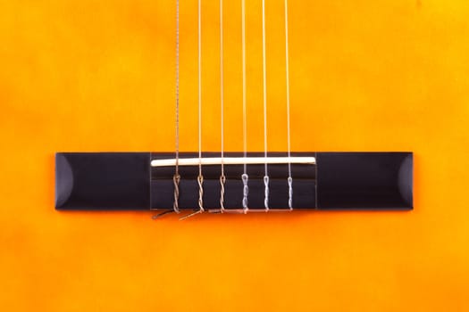 Detail of orange wooden classical acoustic guitar.