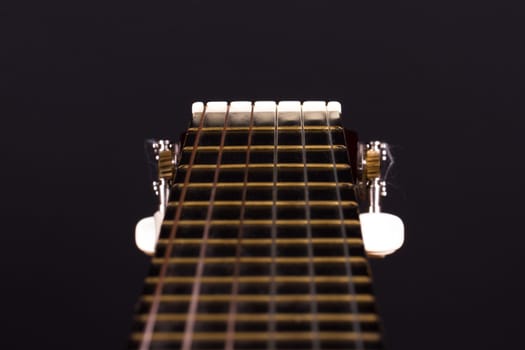 Detail view of classical guitar over black background.