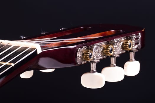 Detail view of fingerboard on classical acoustic guitar over black background.