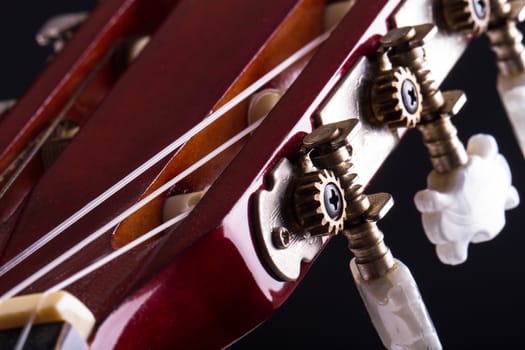 Close up view of fingerboard on classic guitar over black background.
