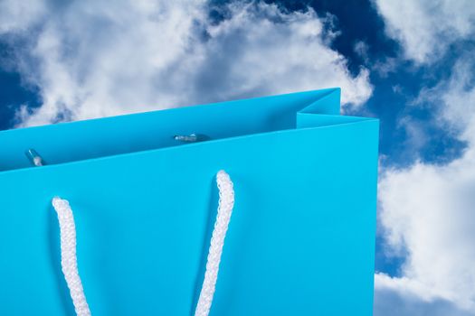 Close up view of blue carton shopping bag with sky background.