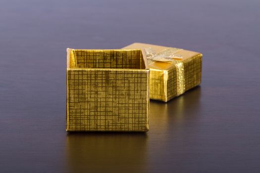 Open, golder colored gift box on wooden table.