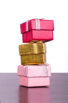 Three colorful gift boxes in row on wooden table, isolated on white background.