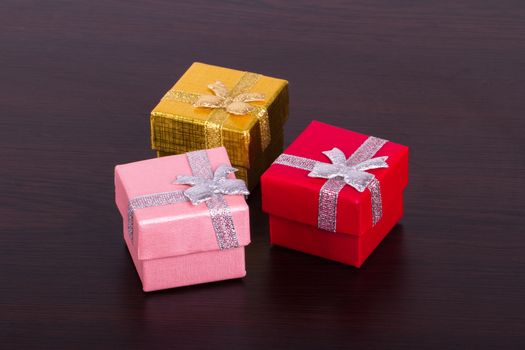 Three colorful gift boxes on wooden table.