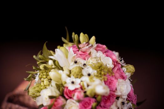 Two golden wedding rings on bridal bouquet 