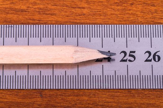 Close up view of wood pencil and steel ruler for engineering drawing on wooden table.