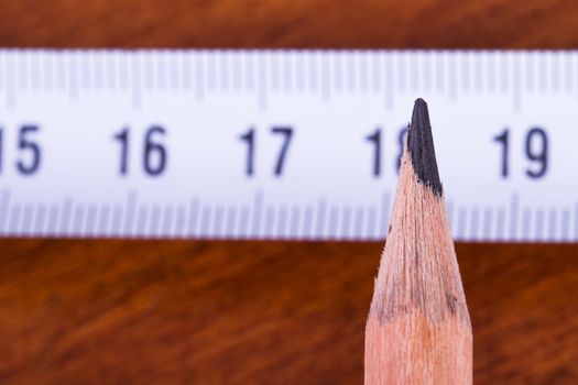 Close up view of wood pencil and steel ruler for engineering drawing on wooden table.