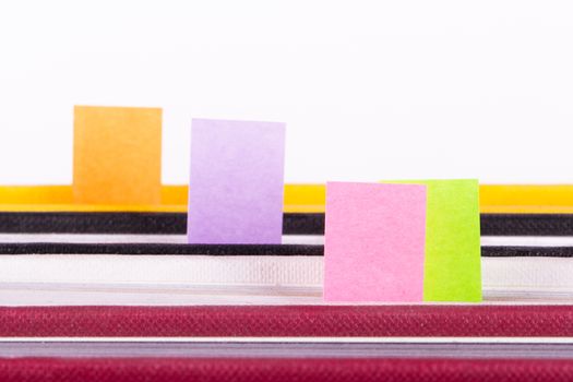 Colorful post it markers inside books, front view, isolated on white background.