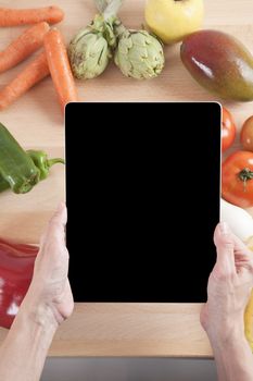 woman hands with blank screen tablet still life fruits and vegetables around on brown wood plank